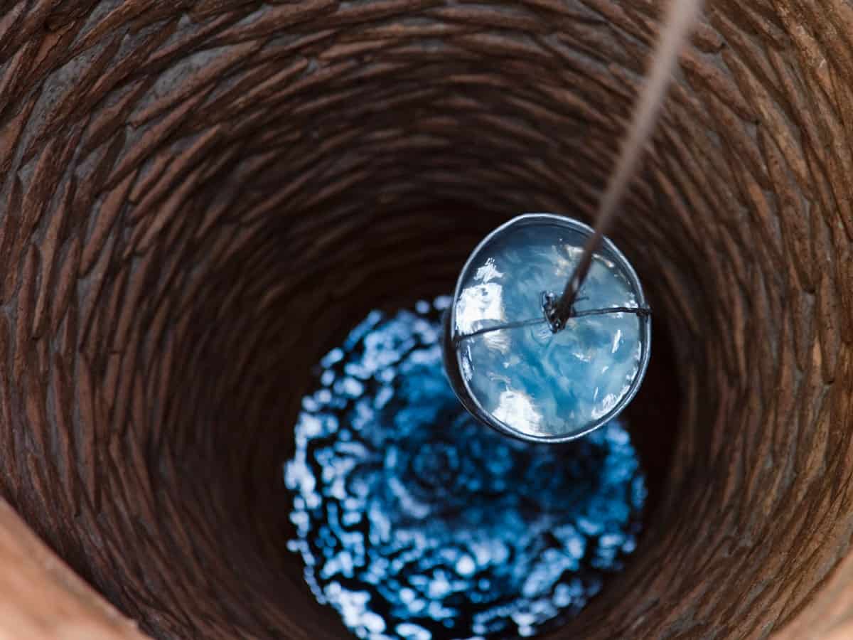 a bucket carrying up well water from a well at a home