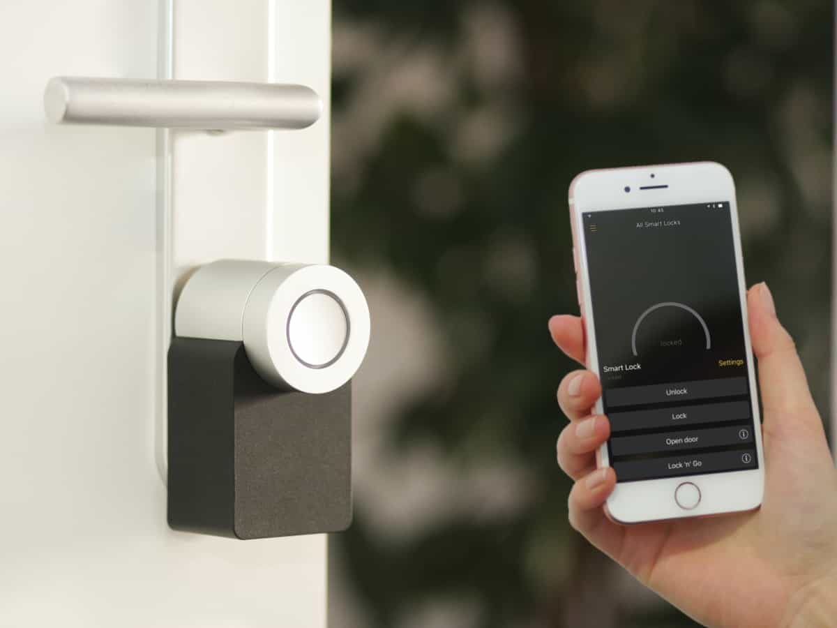 a phone up next to a smart lock and door to unlock and disarm