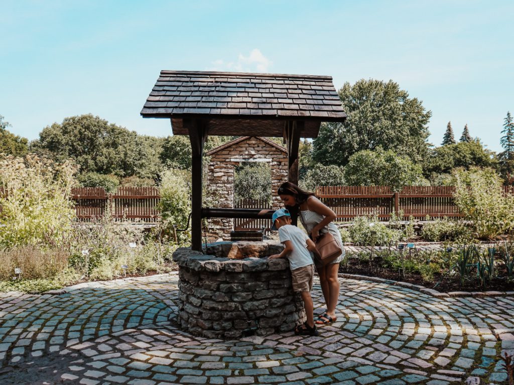 two people leaning over a well to get fresh water