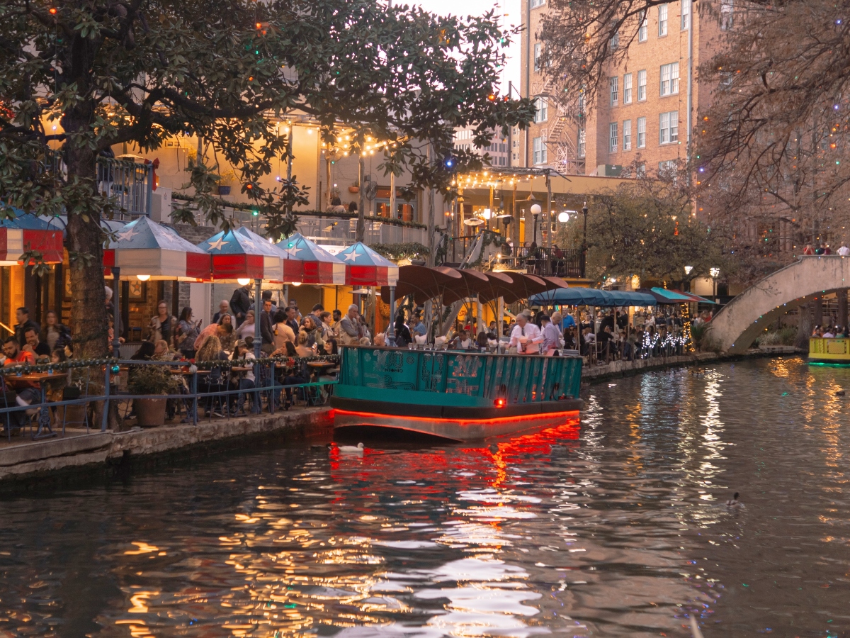the san antonio riverwalk with a boat on the water and restaurants to the side