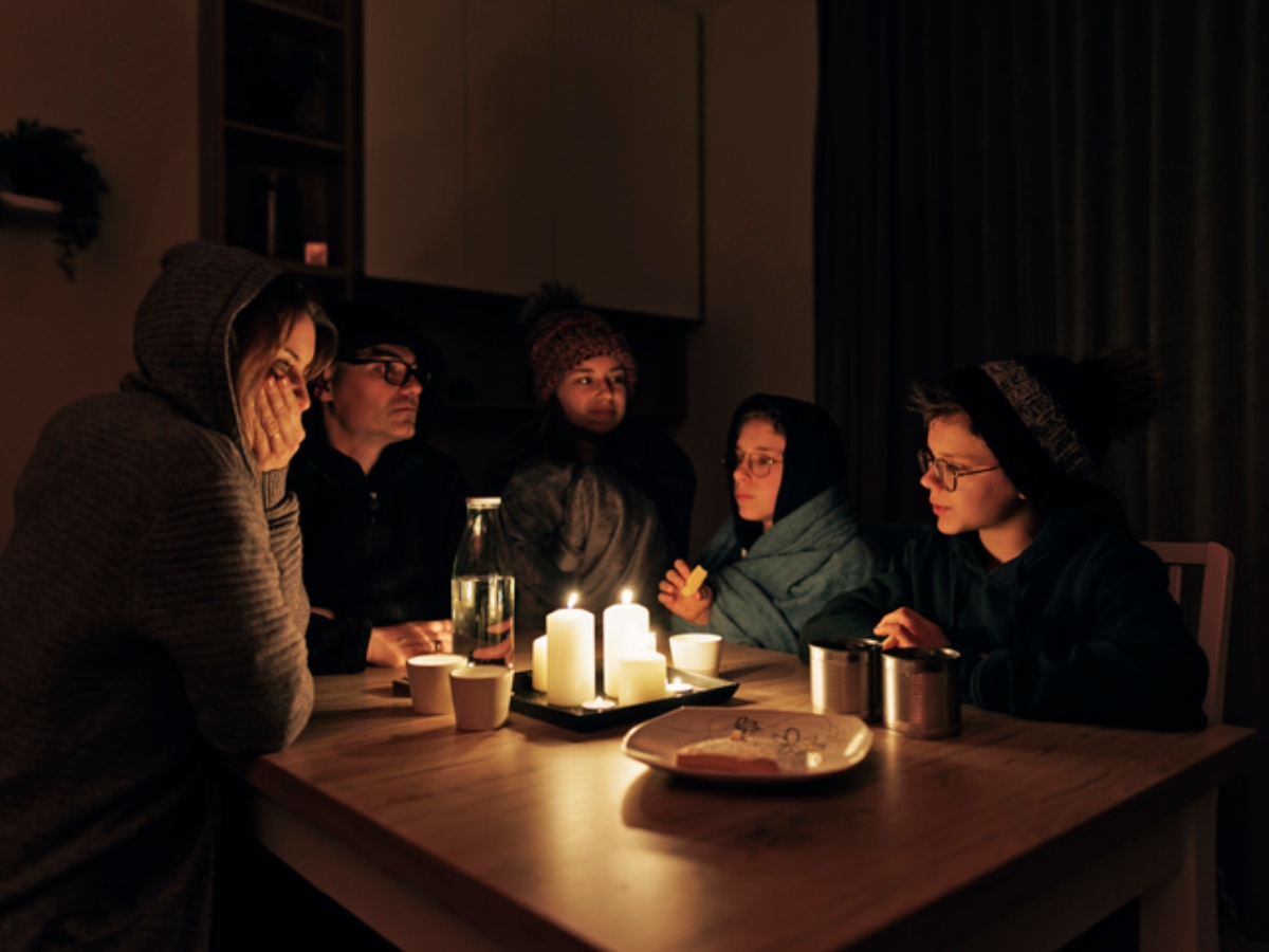 a family sitting around a candle during a power outage