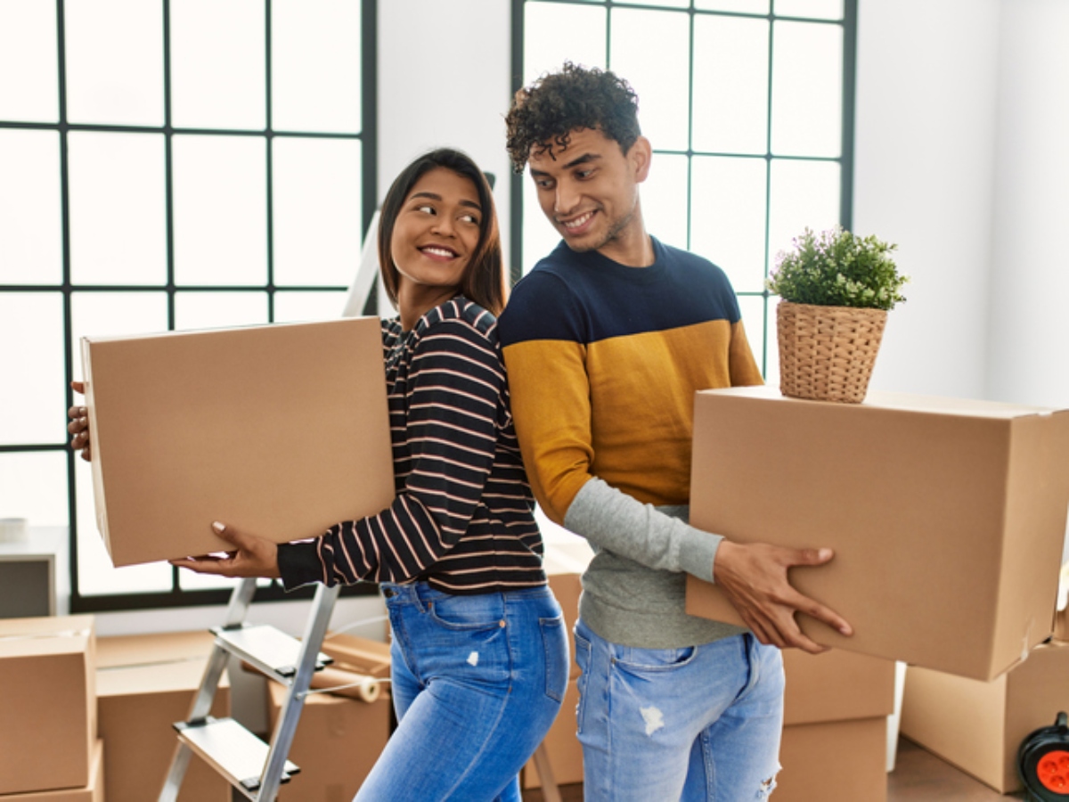 a woman and man back to back holding moving boxes as part of a new home or rental 