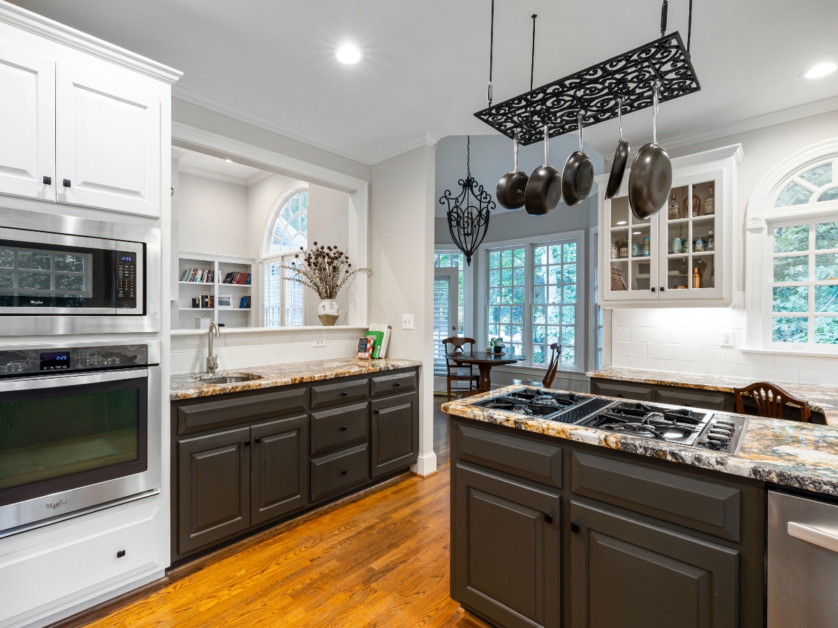 an overview of a kitchen with an oven, sink, microwave, and hanging pots and pans