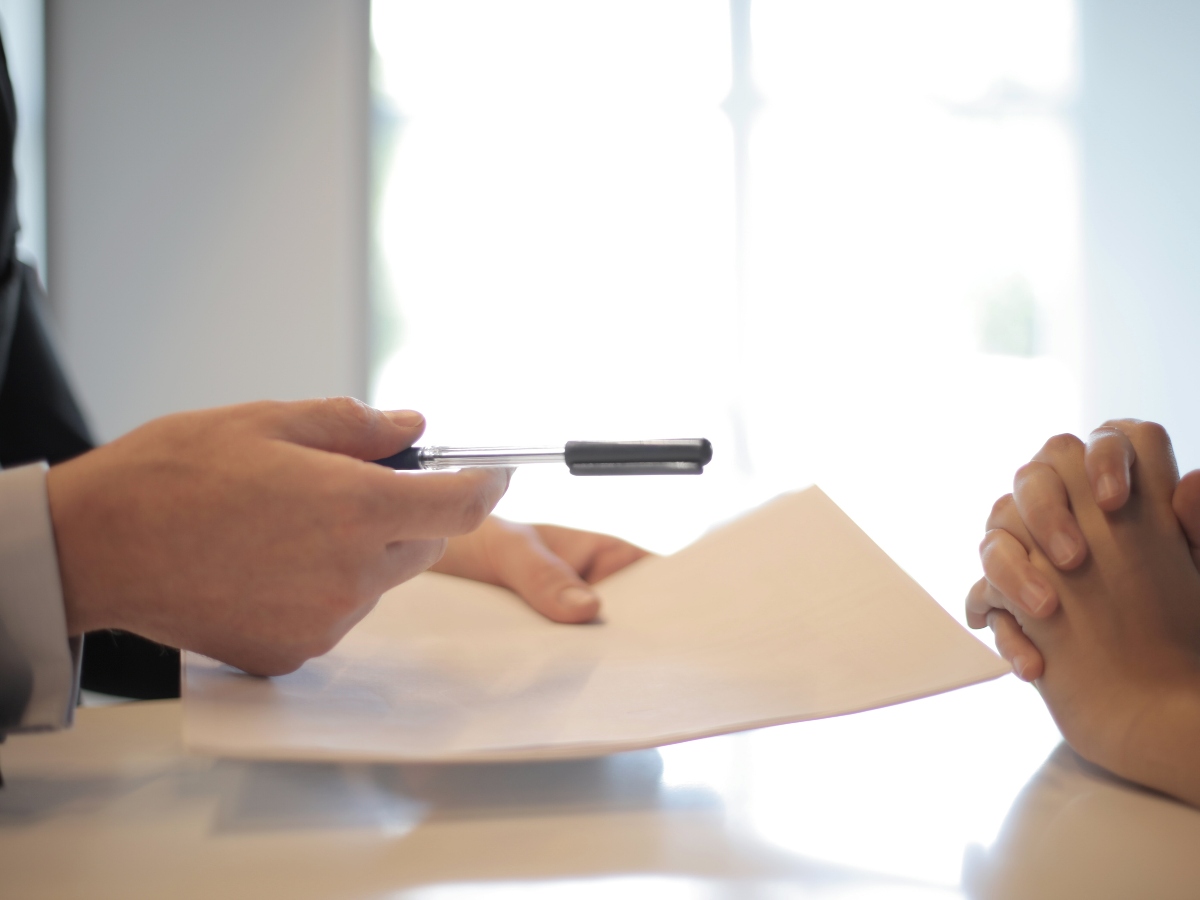 two hands with someone holding a document and pen