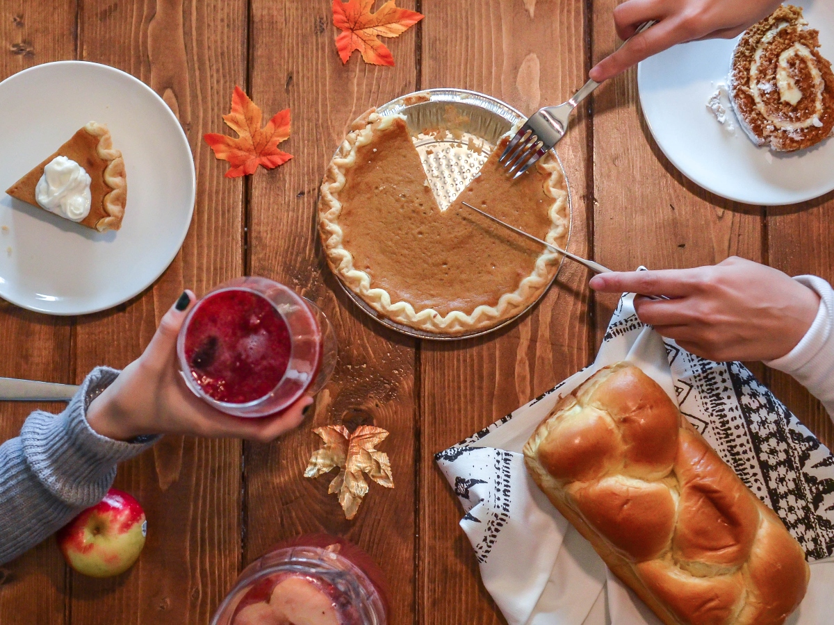 an overhead shot of thanksgiving food, such as pumpkin pie and cranberry drinks
