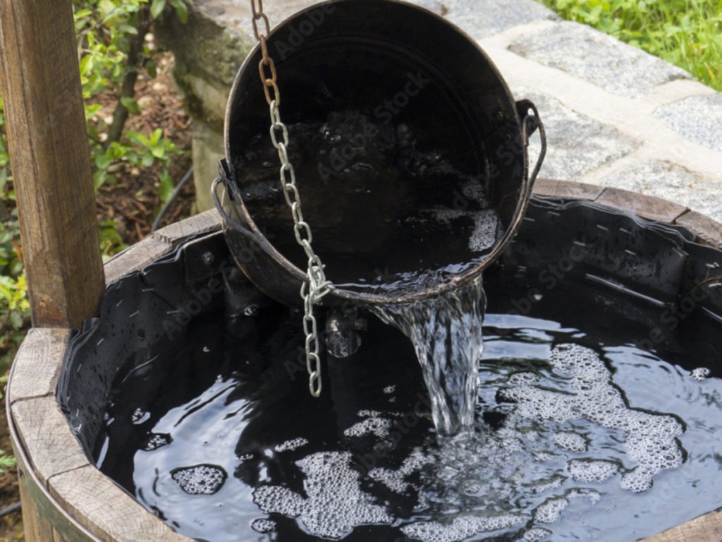 a bucket of water coming out of a well water system