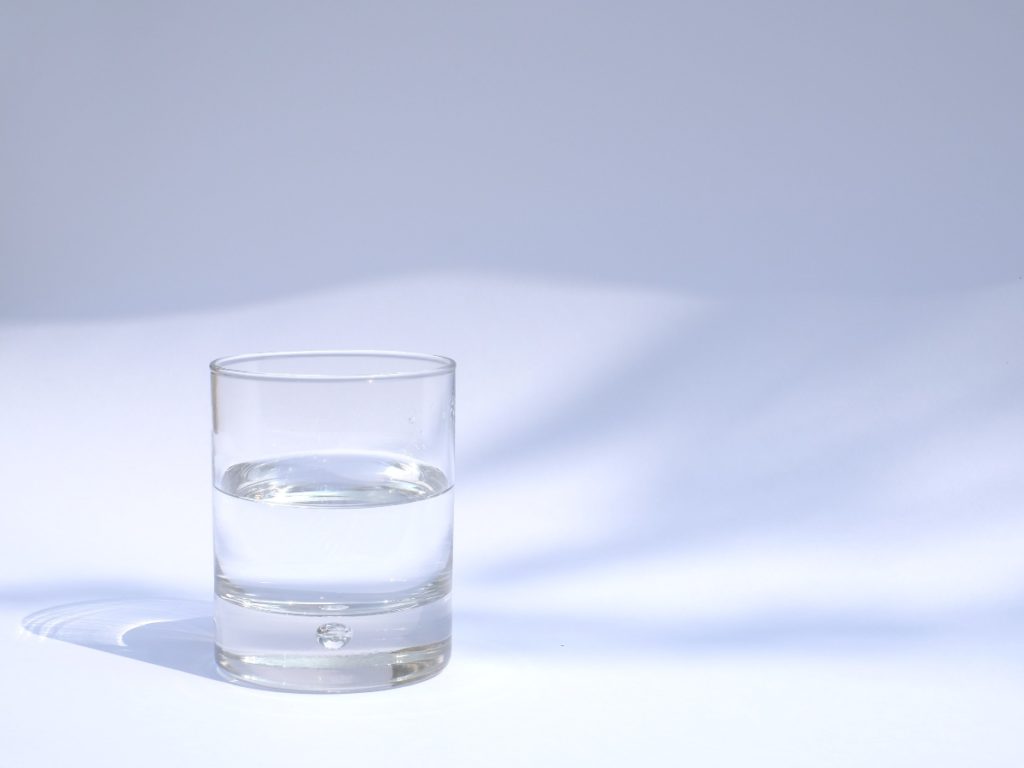 a glass of water against a plain background