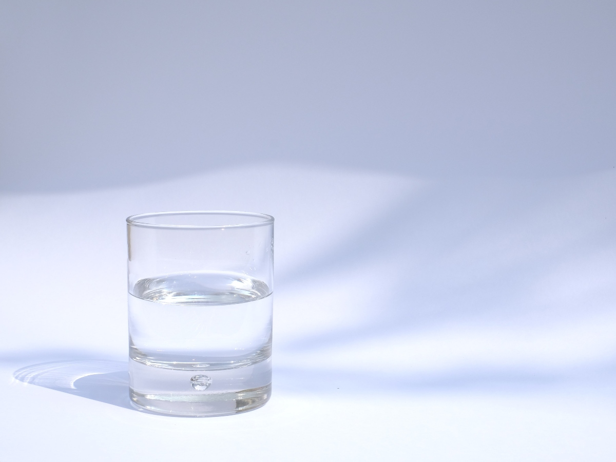 a glass of water against a plain background