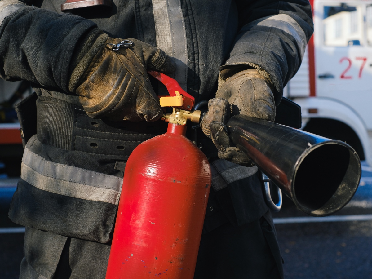 a firefighter holding a fire extinguisher towards a home