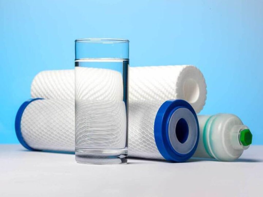 a glass of water in front of three reverse osmosis (RO) water filters