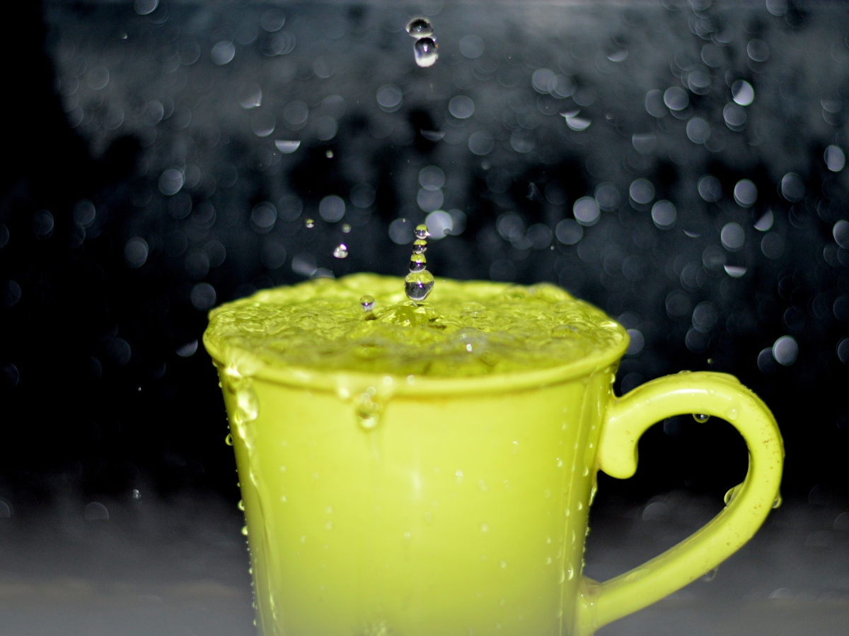 a cup of water in a green mug, water being poured into the mug