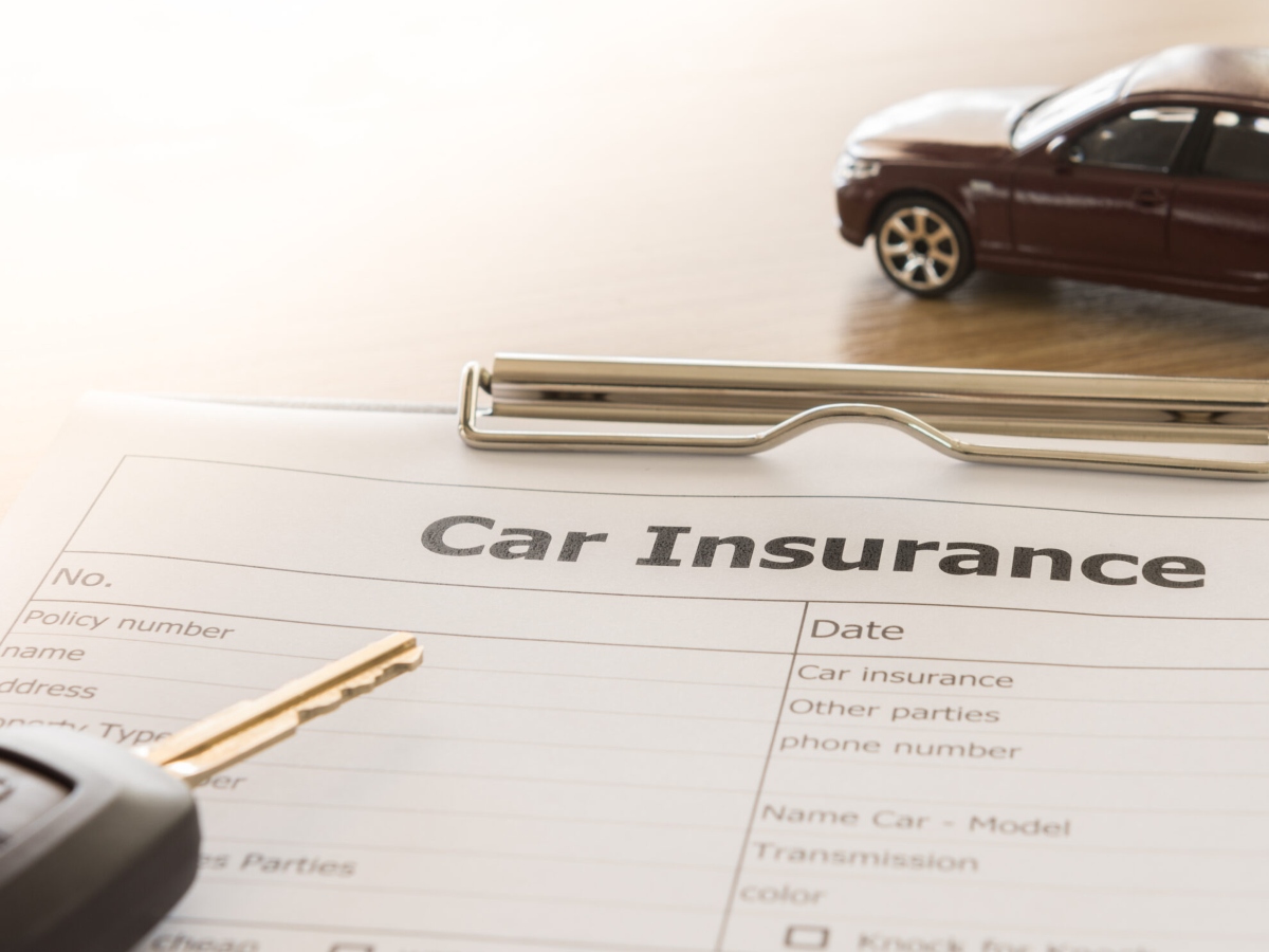 car insurance application form with car model and key remote on desk.