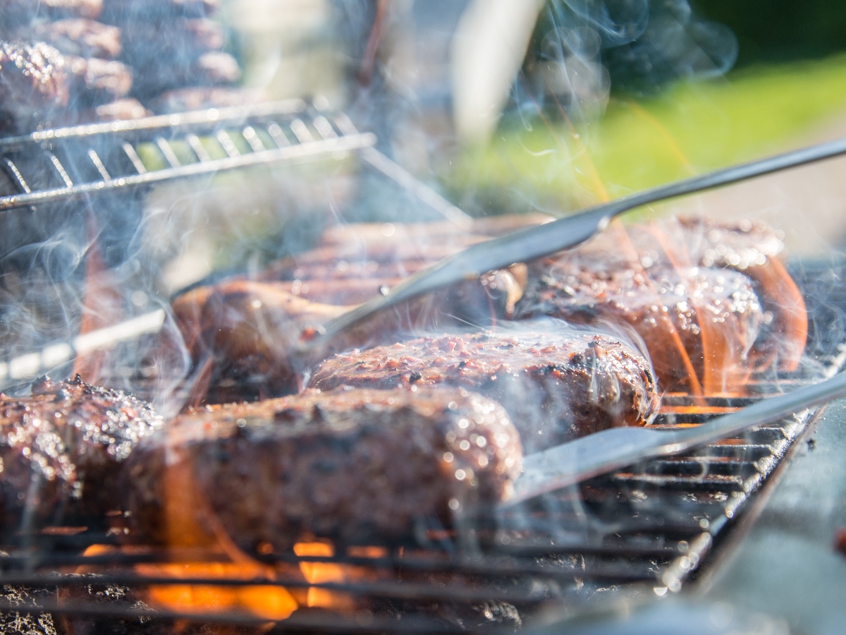 a hand flipping a burger on the grill during summer