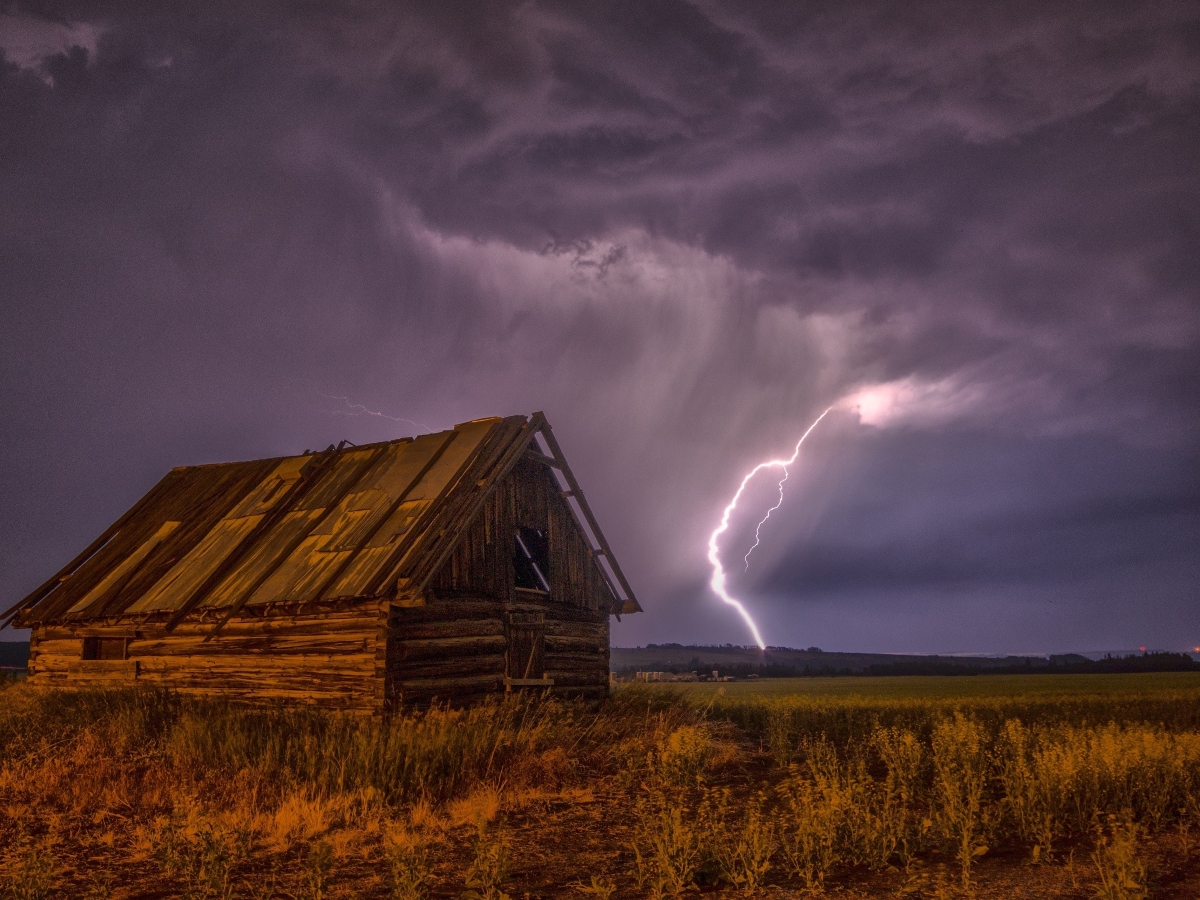 a lightning strike in the sky down to a field during a storm