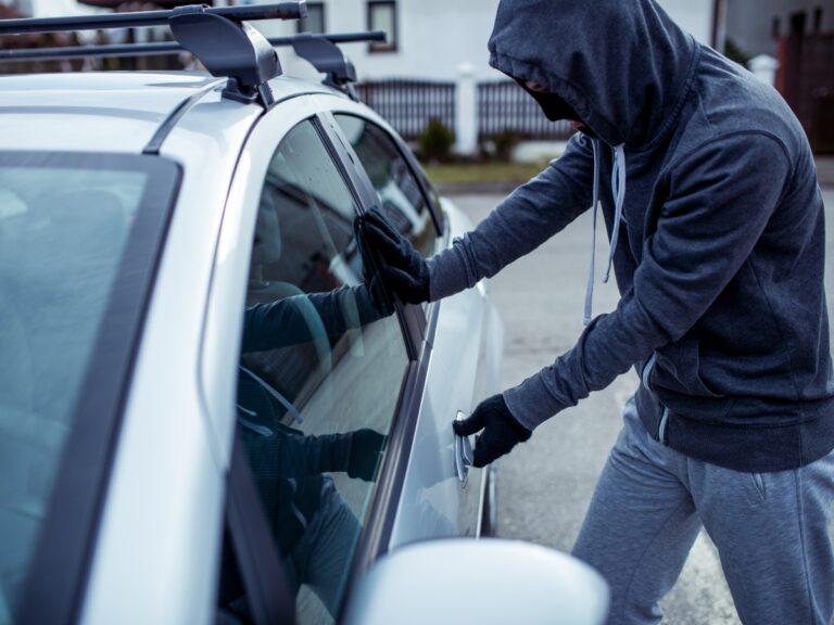 a thief breaking into a car before stealing it