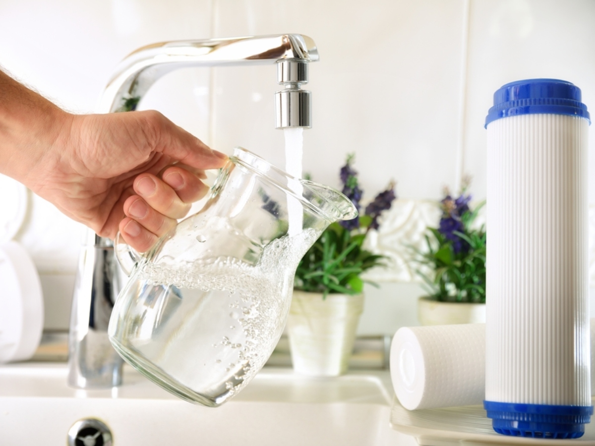 a coconut shell carbon water filter next to a pitcher of water filling from the sink