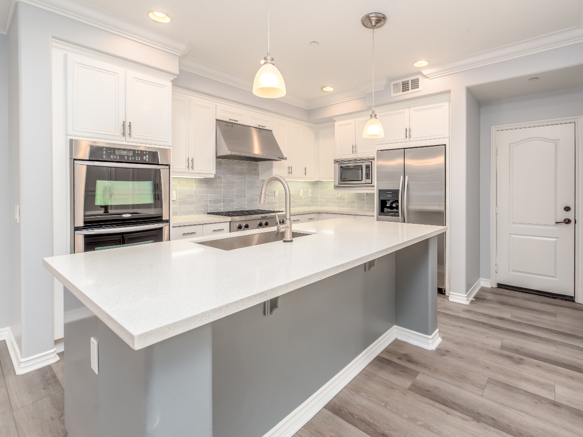 an all white kitchen with oven, sink, microwave and refrigerator