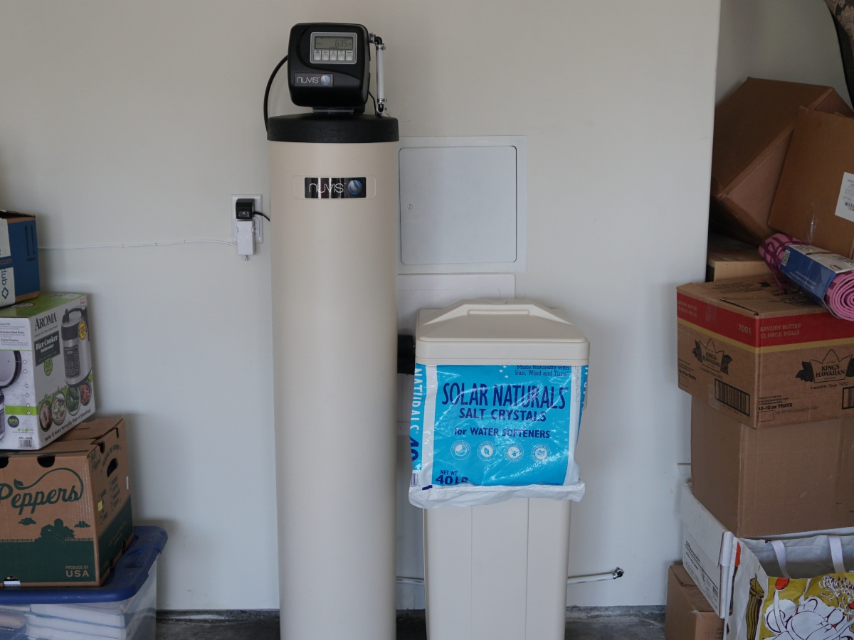 a bag of water softener salt against a water softening system in someone's garage