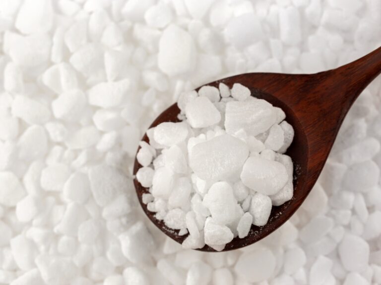 a wooden spoon holding salt pellets from a water softening system