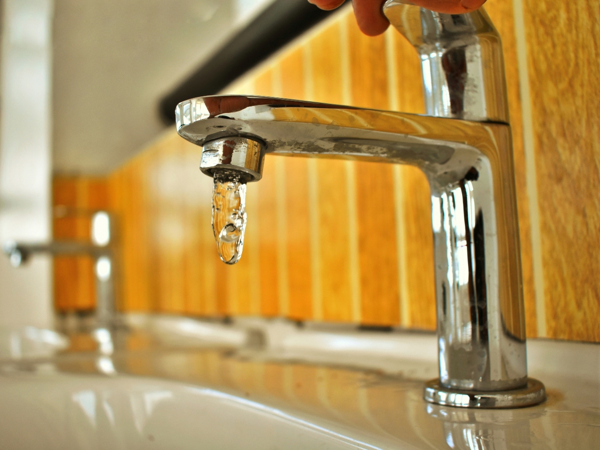 a stainless steel faucet with water dripping into the sink