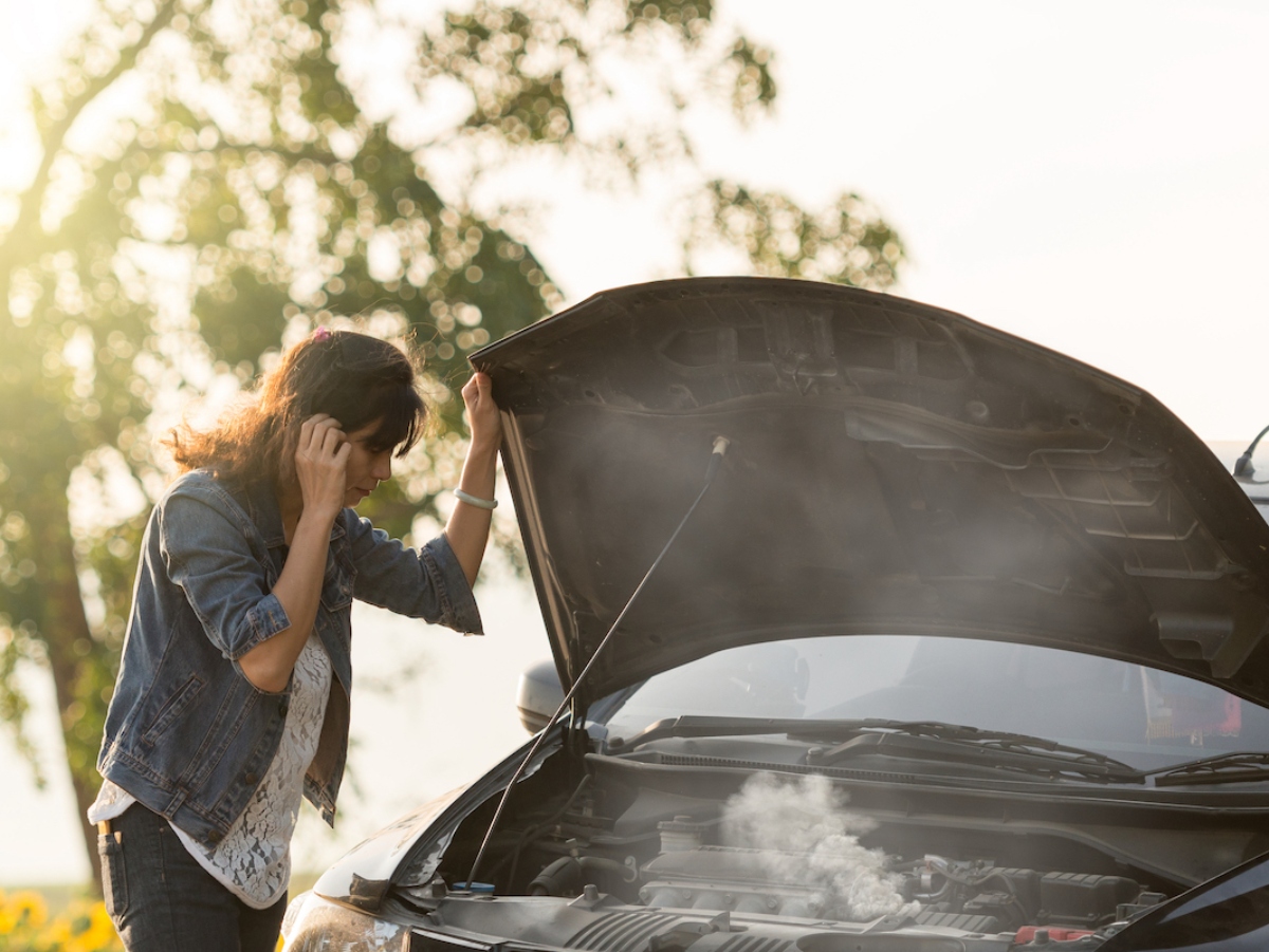 woman standing next to an overheated car