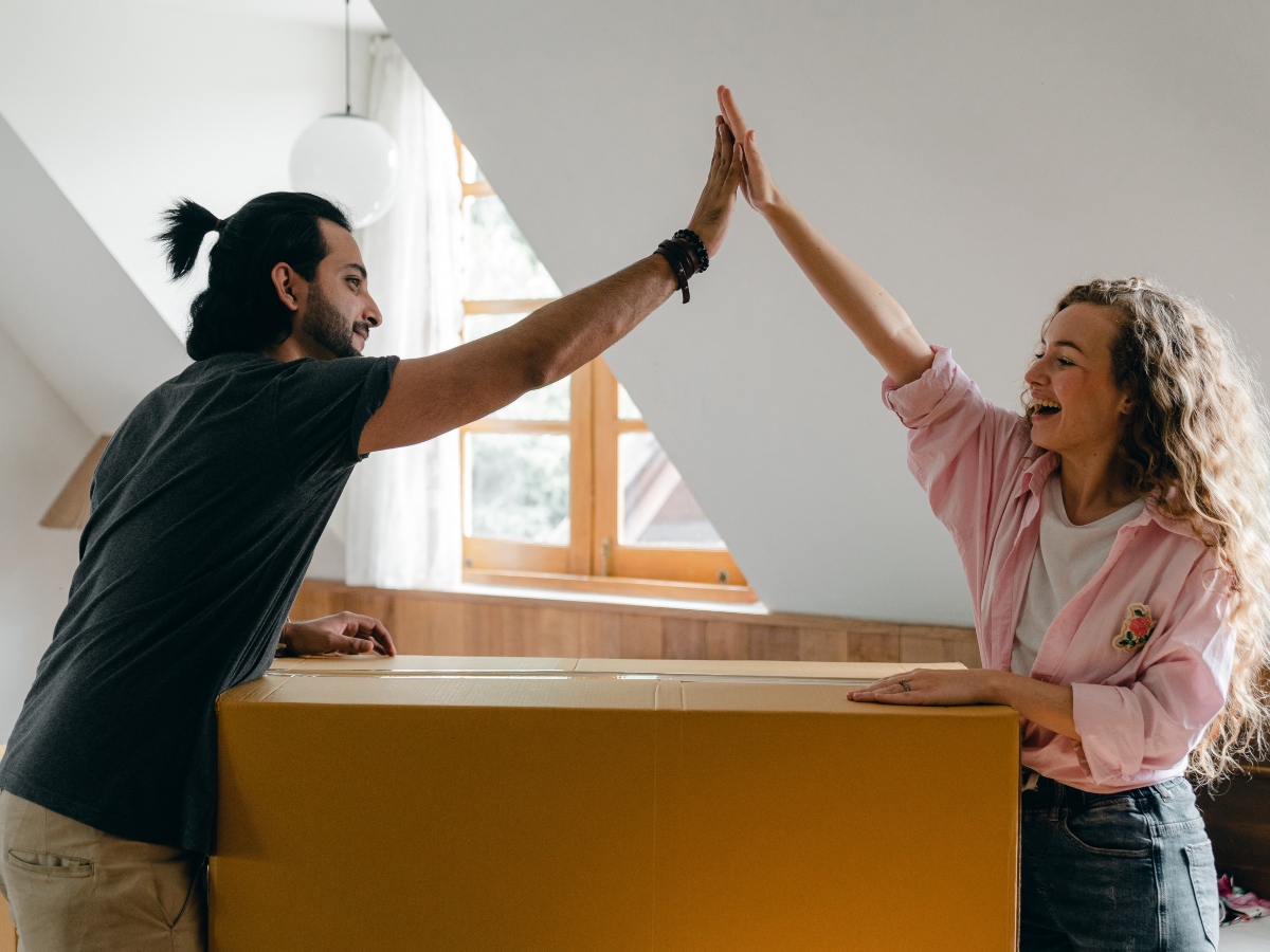 a couple high fiving while standing over a moving box