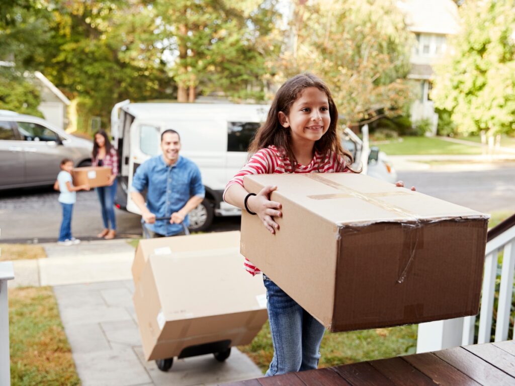 Children Helping Unload Boxes From Van On Family Moving In Day