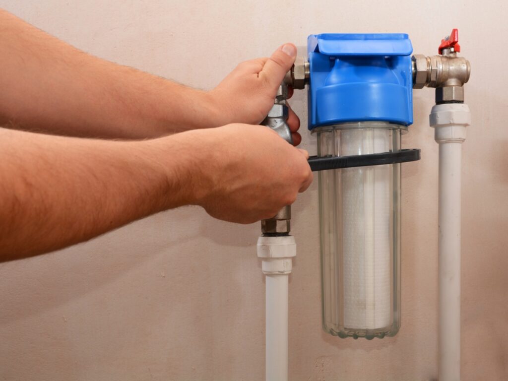 a person using a tool with a water filter providing some maintenance to keep the system running normally