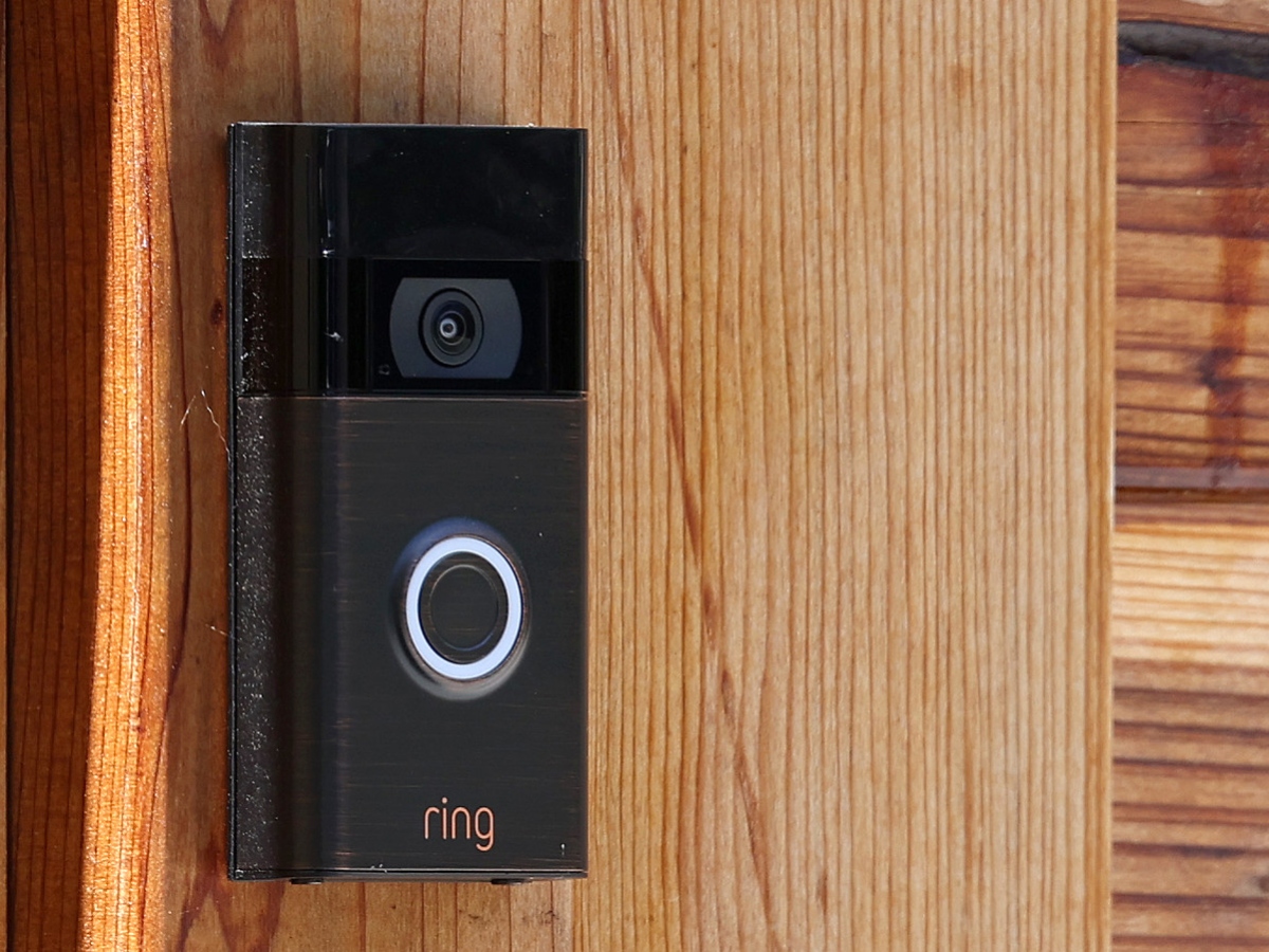 a black ring doorbell against a wooden door